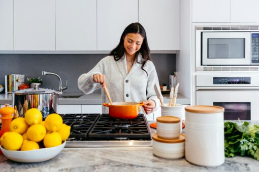 woman cooking in kitchen with orange dutch oven pot