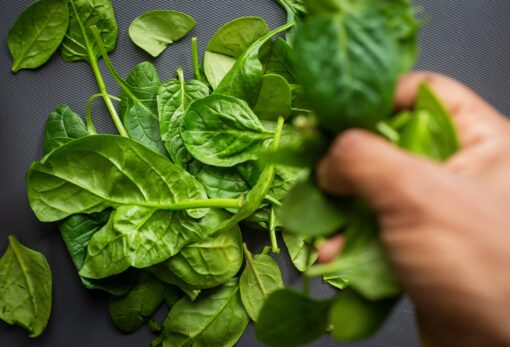 hand tossing fresh baby spinach