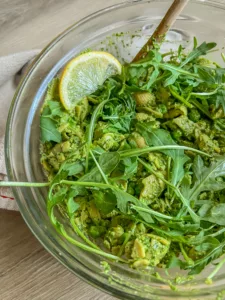 Bowl of pasta salad with green sauce and arugula