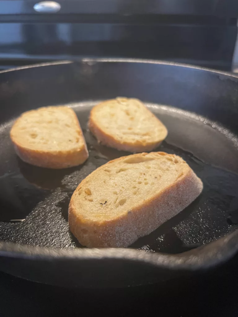 sliced sourdough bread frying in oil in skillet