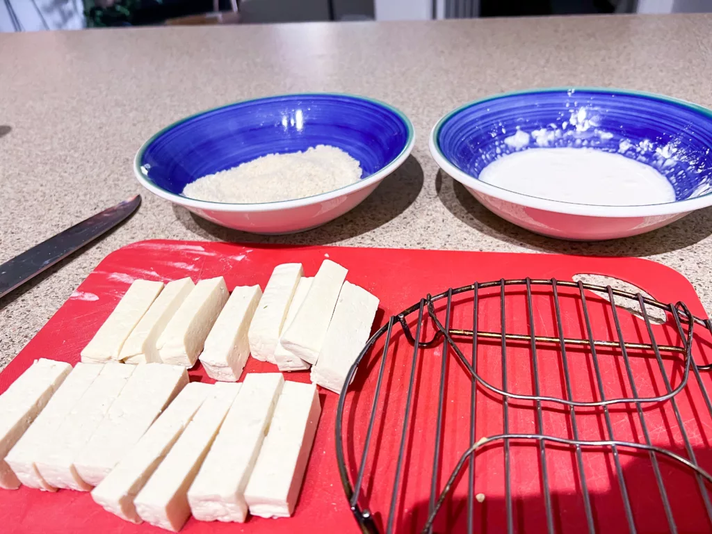 tofu cut up into strips on red cutting board