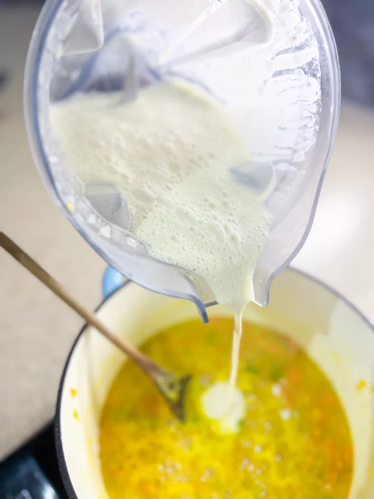 adding cashew sauce to gnocchi soup