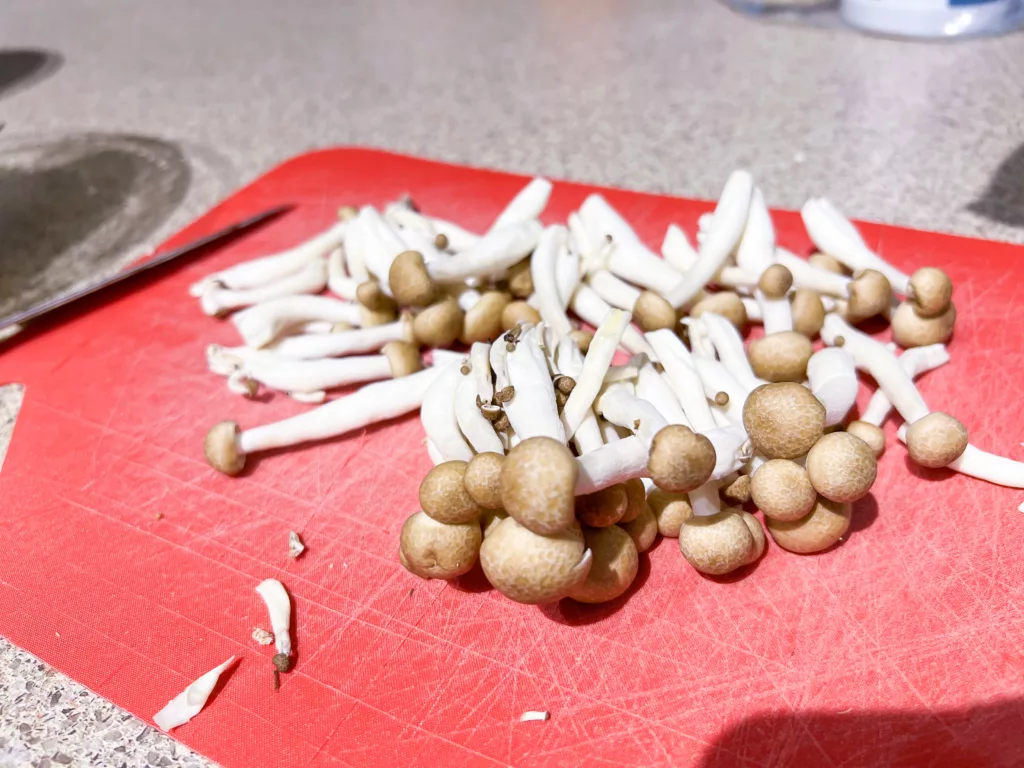 Shimeji mushrooms on red cutting board