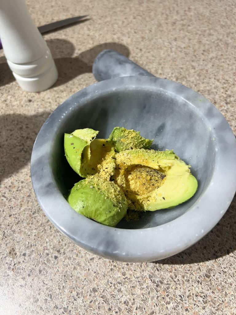 un mashed avocado in grey pestle and mortar