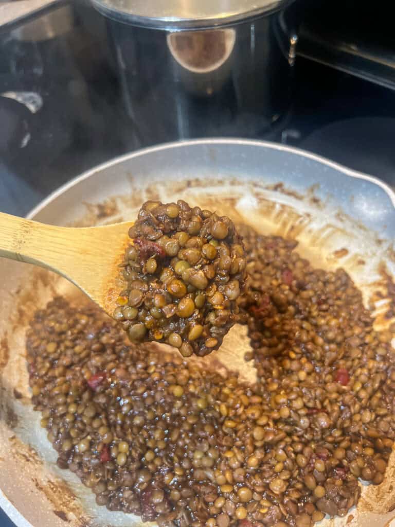 cooked lentils on wooden spoon