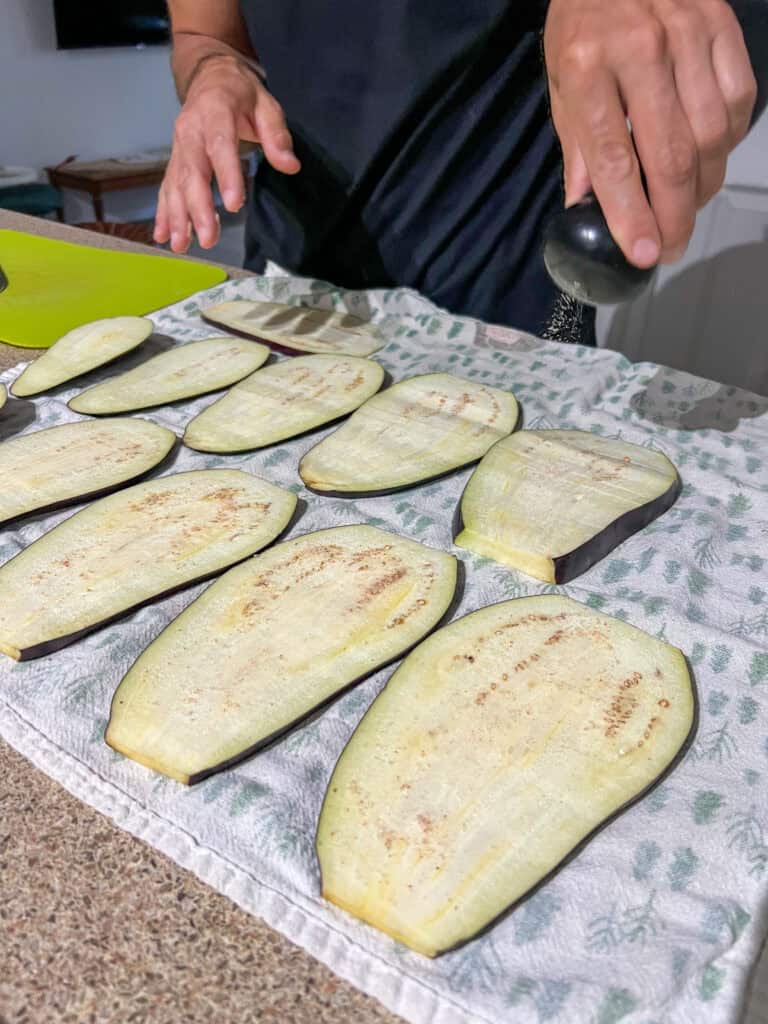 adding salt to the eggplants on towel