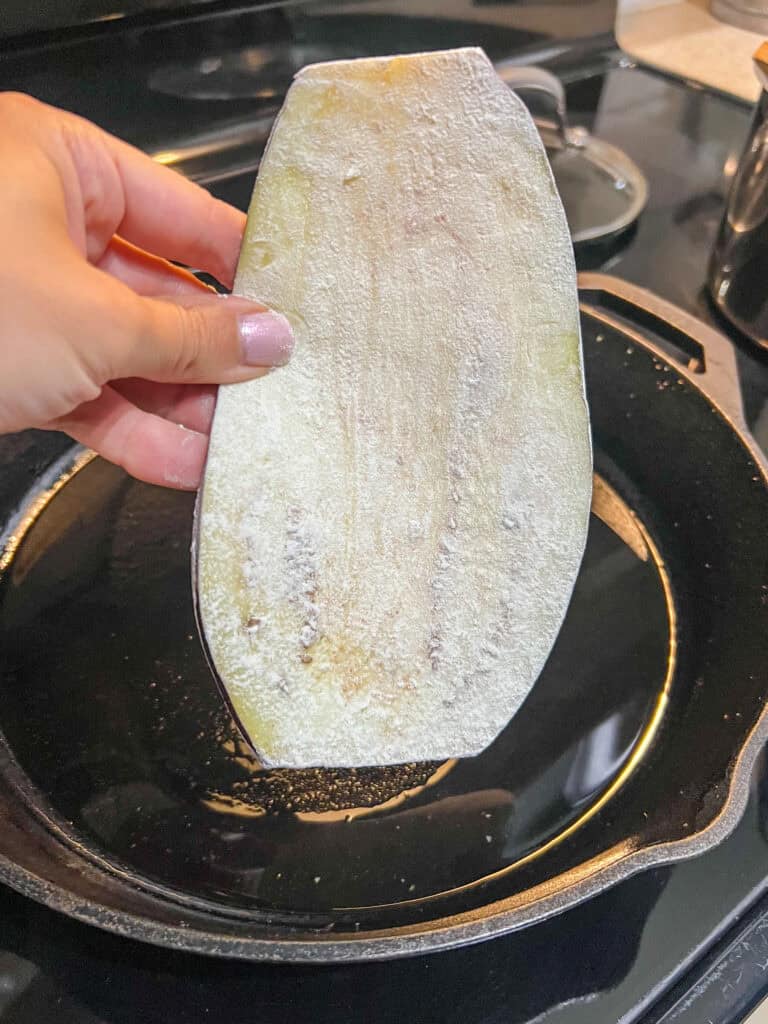 adding the eggplant to heated cast iron pan