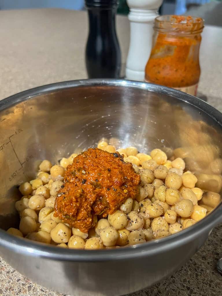 tomato pesto on chickpeas in a stainless steel bowl