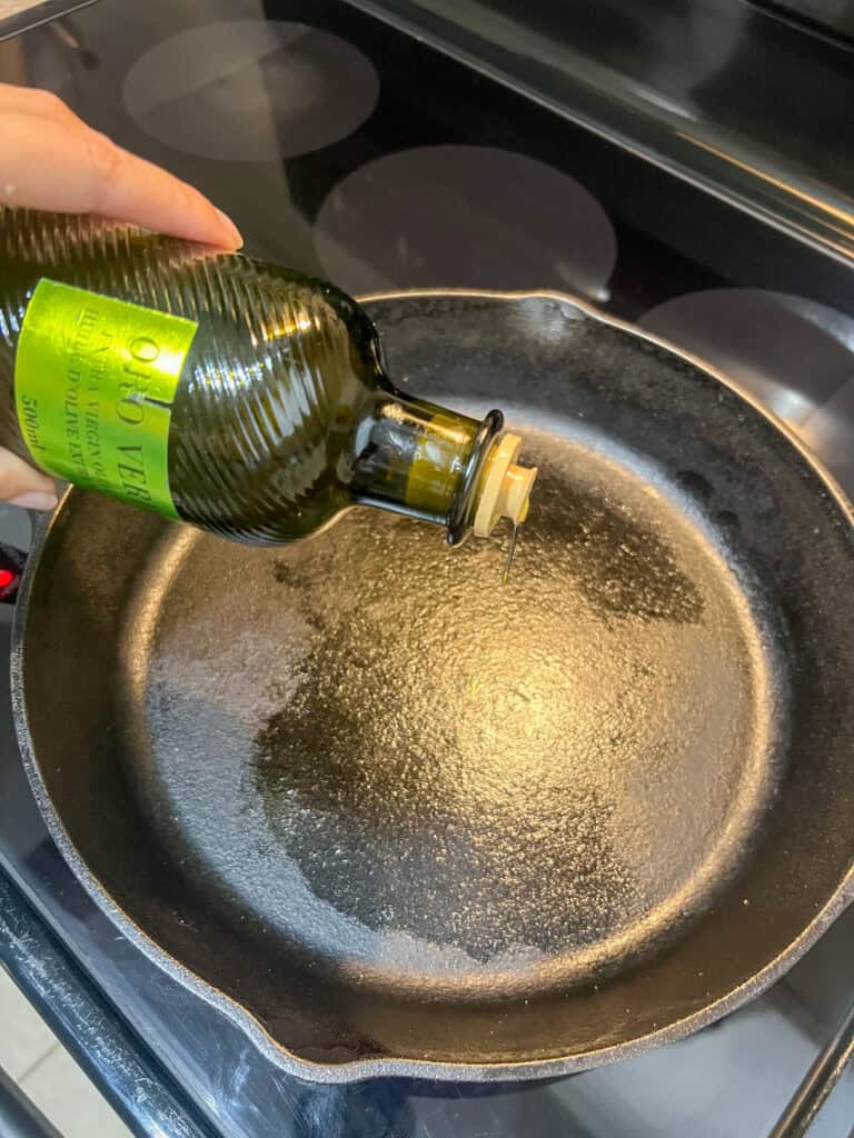 olive oil going onto a cast iron frying pan