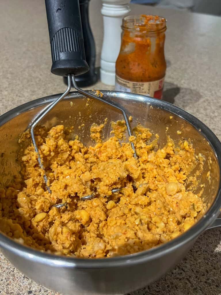 crushed up chickpea mixture in stainless steel bowl