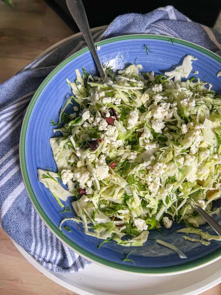 greek cabbage salad in large blue bowl