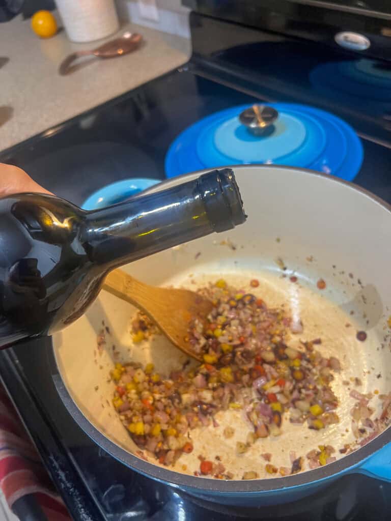 adding balsamic vinegar to the spices added to the carrots and onion in dutch oven cooking