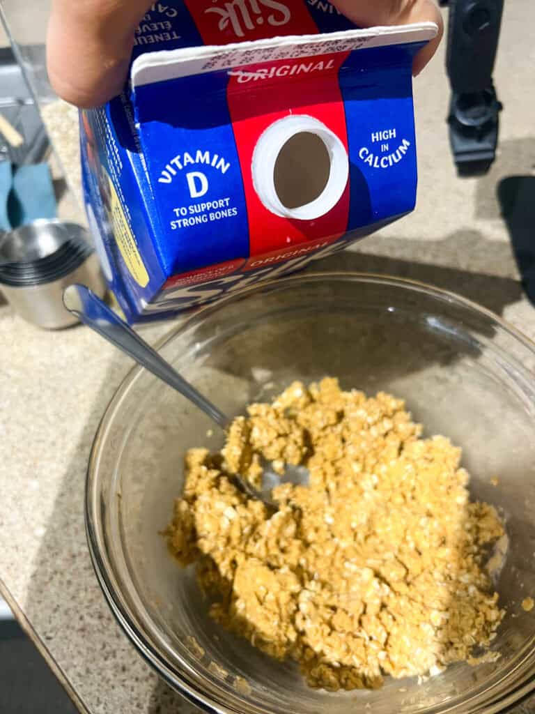adding milk to the clear mixing bowl with ingredients