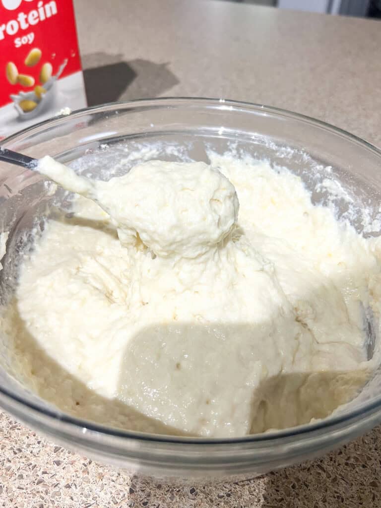 lemon loaf dough in clear mixing bowl with spoon