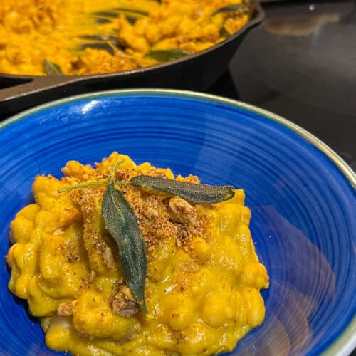 butternut squash bean dish with crispy sage leaves on top in blue bowl
