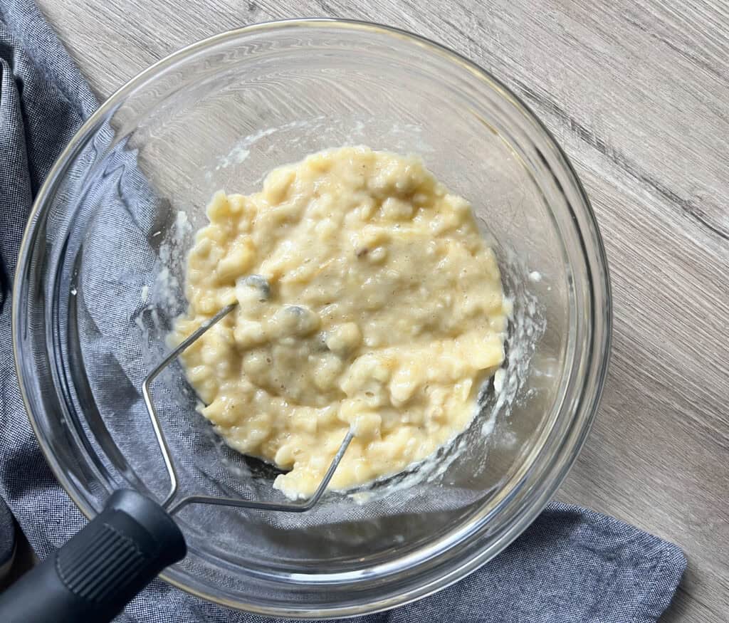 mashed up banana in clear mixing bowl