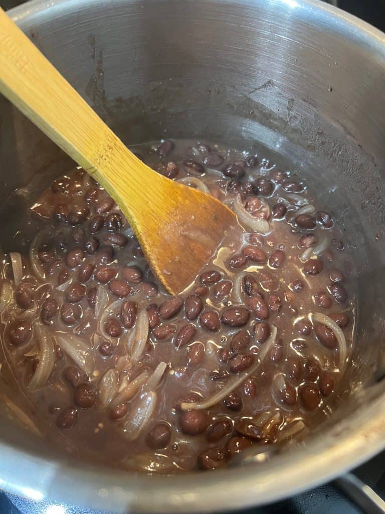 black beans and onions cooking in stainless steel pot
