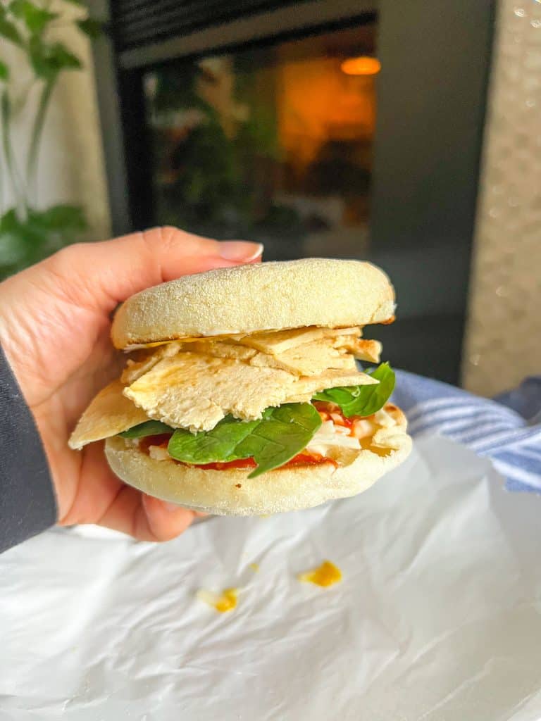 hand holding tofu deli slices on sandwich