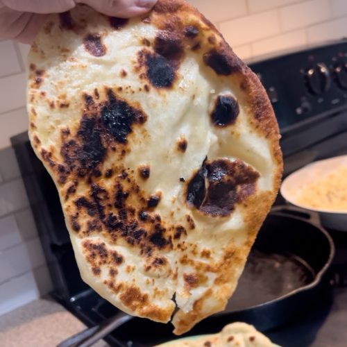 protein naan being held up by cast iron pan