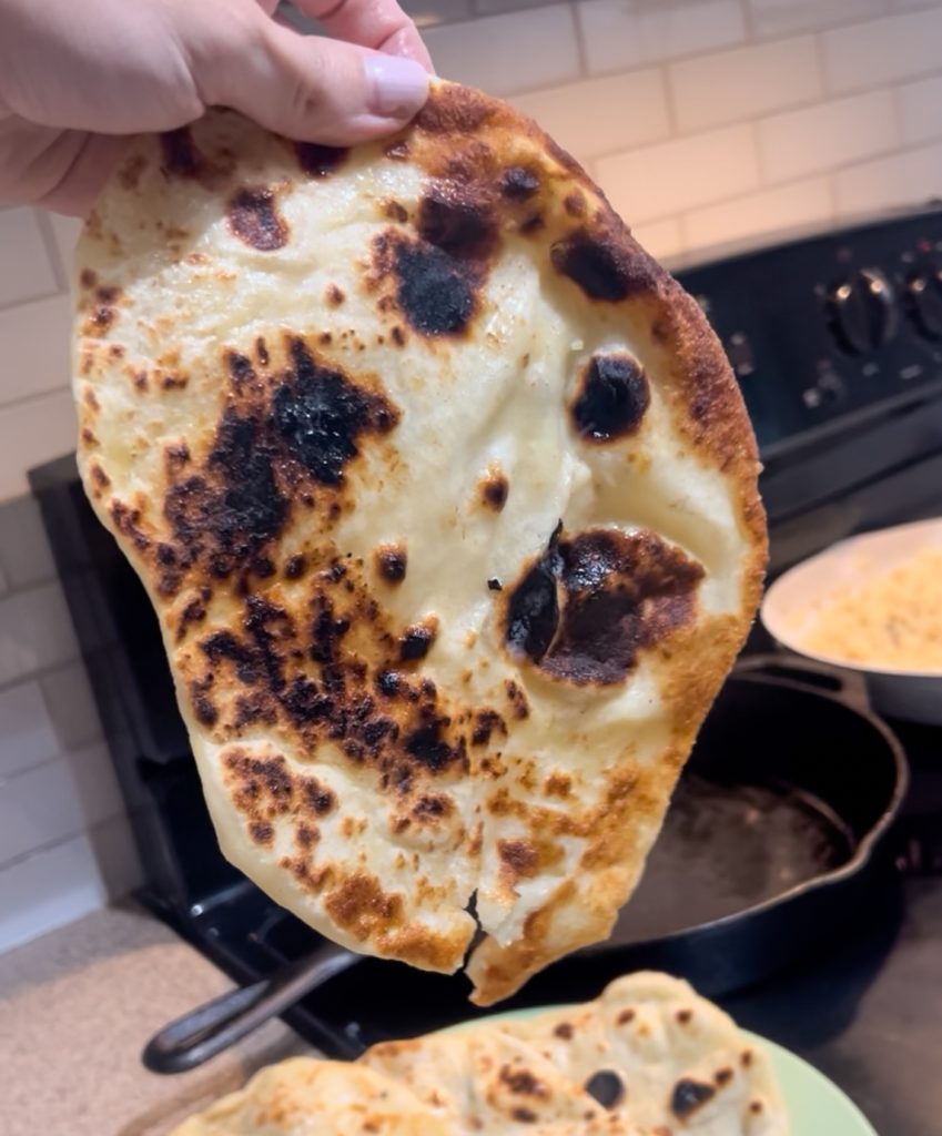protein naan being held up by cast iron pan