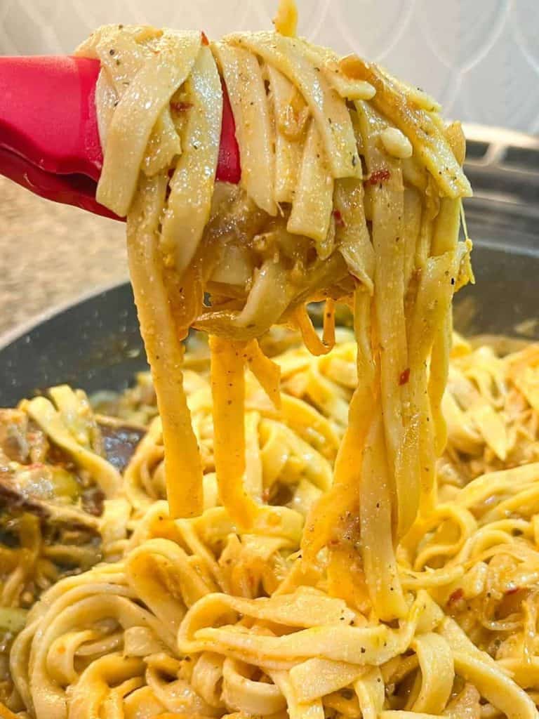 vegan caramelized onion pasta being held up long noodles